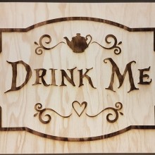 gravure sur bois: texte "Drink Me" et éléments décoratifs